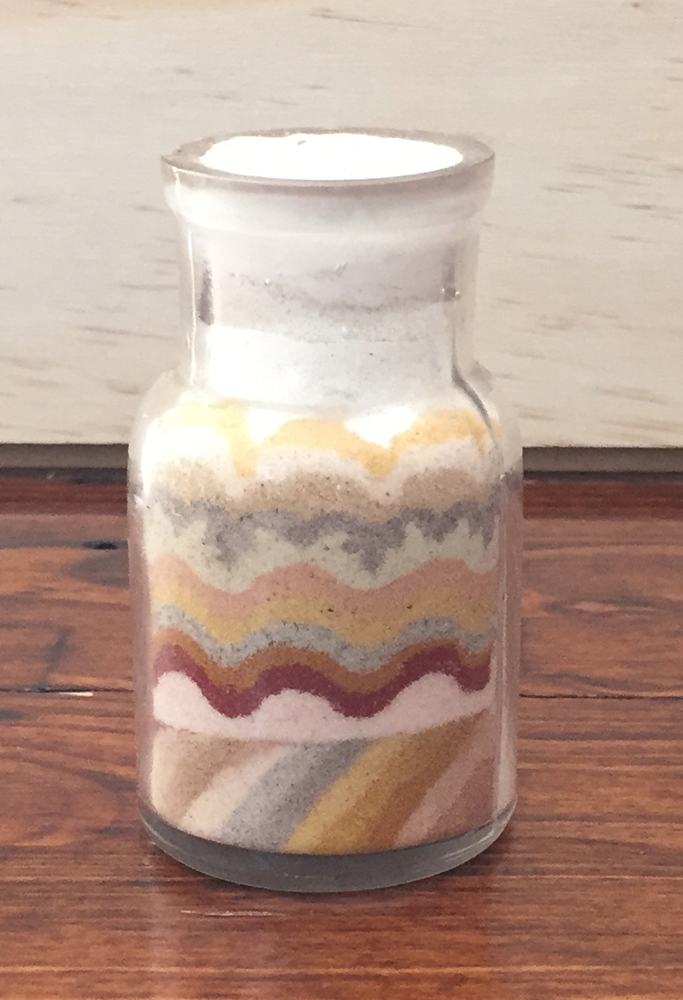 A bottle of sand from Minnehaha, in a even pattern.