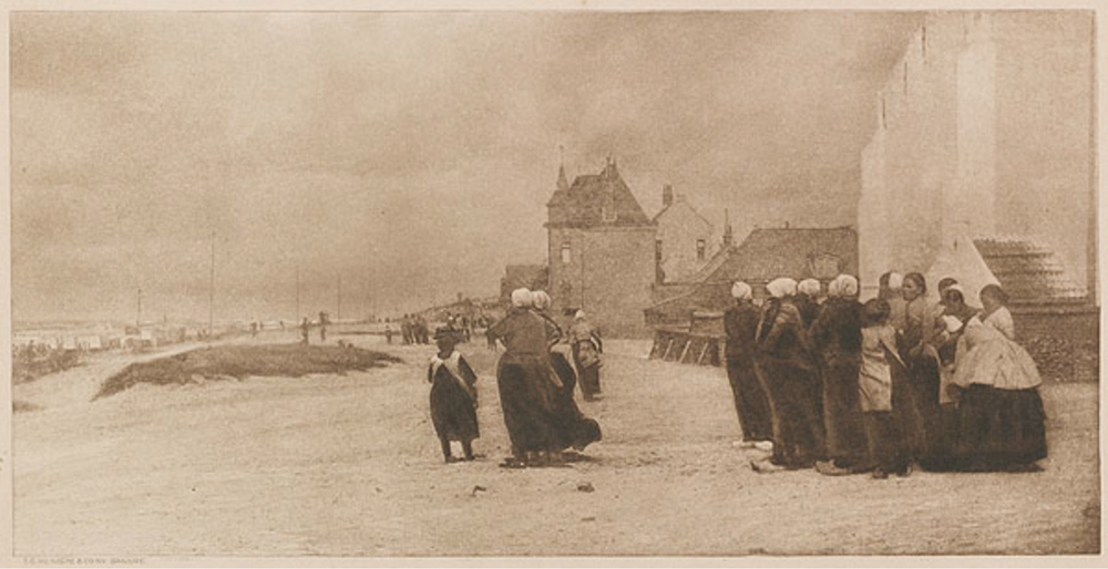 A group of women on the sore, staring out to the sea that is just out of frame on the left.