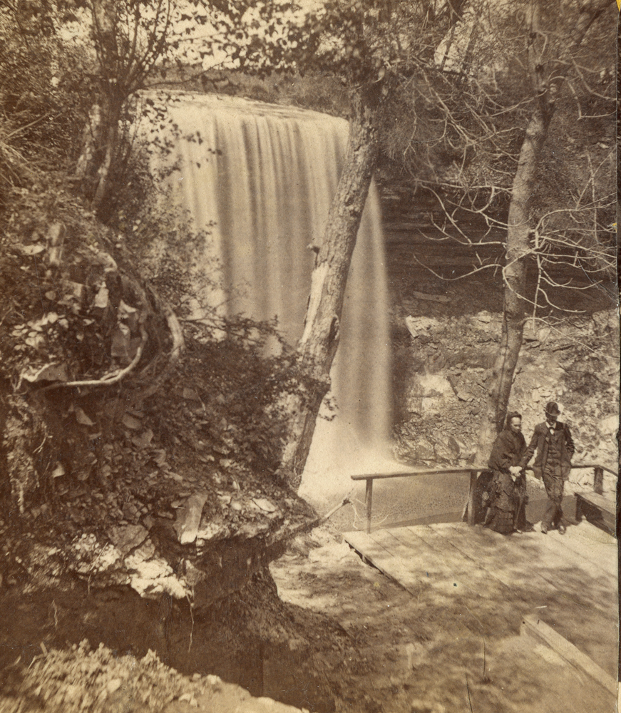 2 people on the side of the Minnehaha gorge, on a wooden platform with tall railings.