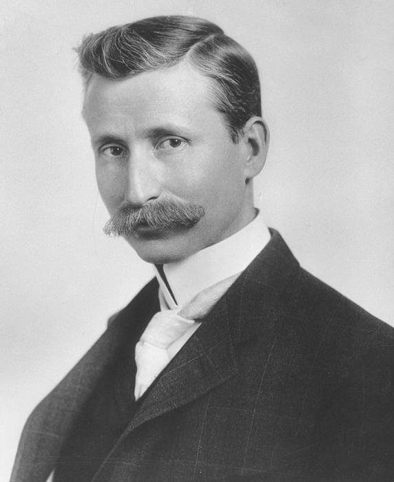 A man with an impressive mustache who is probably in his 30s.